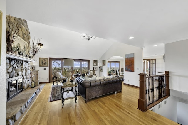 living room with baseboards, arched walkways, light wood-type flooring, a fireplace, and recessed lighting