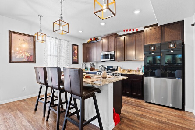 552 Other, Rapid City, SD 57703 - kitchen featuring dark brown cabinets, light wood-style flooring, appliances with stainless steel finishes, and a center island with sink