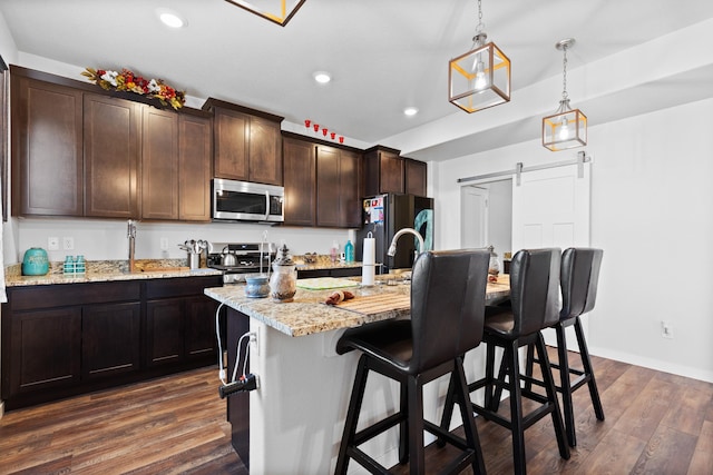 552 Other, Rapid City, SD 57703 - kitchen with dark brown cabinetry, dark wood-type flooring, a barn door, appliances with stainless steel finishes, and a breakfast bar area