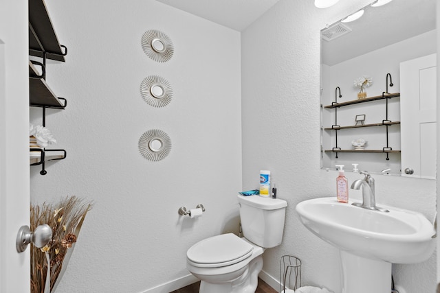 552 Other, Rapid City, SD 57703 - half bath featuring visible vents, toilet, a sink, a textured wall, and baseboards