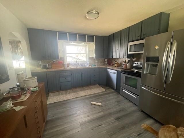 1021 Omaha St, Belle Fourche, SD 57717 - kitchen with appliances with stainless steel finishes, dark wood-type flooring, and a sink