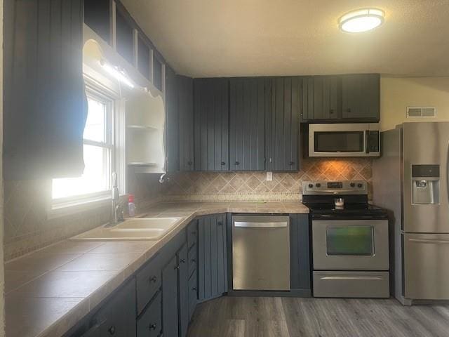 1021 Omaha St, Belle Fourche, SD 57717 - kitchen with stainless steel appliances, a sink, tasteful backsplash, visible vents, and tile countertops