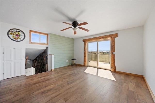 unfurnished living room with baseboards, a ceiling fan, plenty of natural light, and wood finished floors