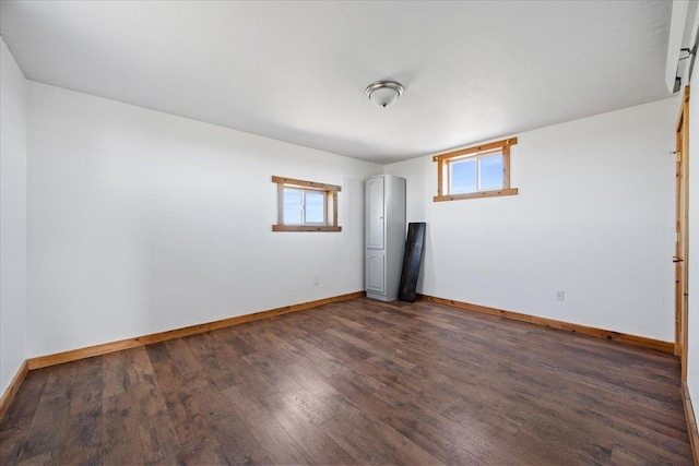 unfurnished room with baseboards and dark wood-style floors