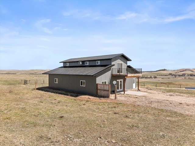 view of side of home featuring a rural view, metal roof, and an outdoor structure