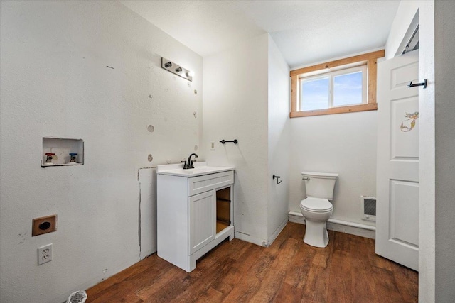 half bath featuring toilet, wood finished floors, and vanity