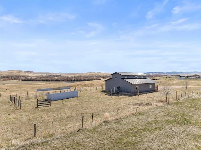 view of yard featuring a rural view, fence, and an outbuilding