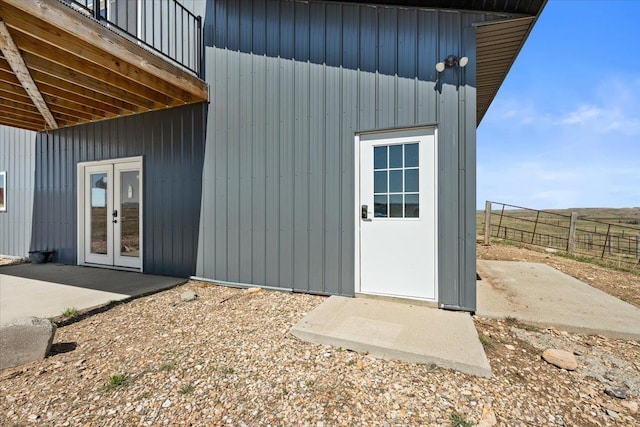 entrance to property with french doors, board and batten siding, and fence