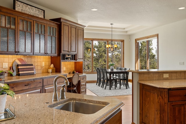 2724 Diamond Oak Pl, Rapid City, SD 57702 - kitchen featuring light stone countertops, decorative light fixtures, a sink, and backsplash