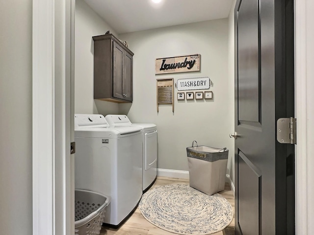 laundry area featuring washer and dryer, cabinet space, light wood-type flooring, and baseboards