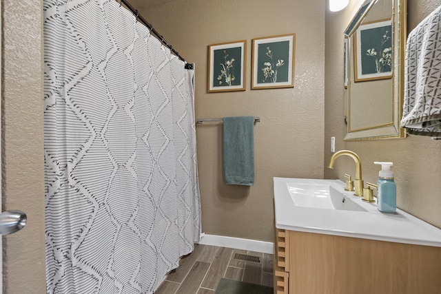 3818 W Main St, Rapid City, SD 57702 - bathroom featuring baseboards, a textured wall, vanity, and wood finish floors