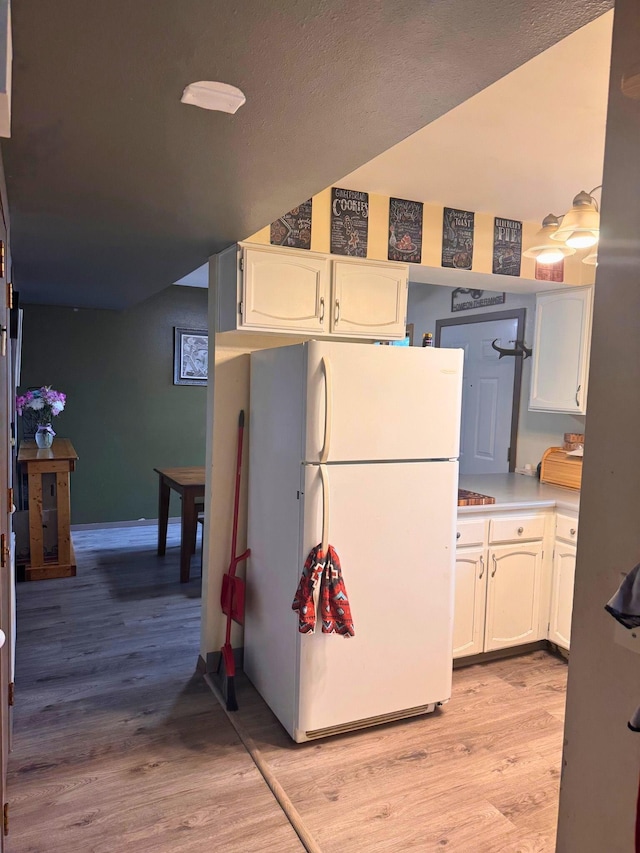 16A Statesboro Dr, Belle Fourche, SD 57717 - kitchen with freestanding refrigerator, white cabinetry, light wood finished floors, light countertops, and baseboards