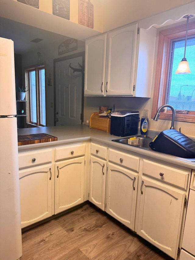 16A Statesboro Dr, Belle Fourche, SD 57717 - kitchen with freestanding refrigerator, wood finished floors, a sink, and white cabinetry