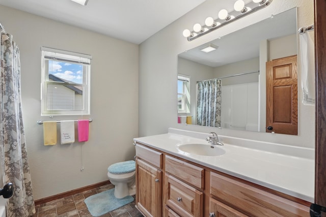 bathroom featuring a wealth of natural light, toilet, baseboards, and vanity