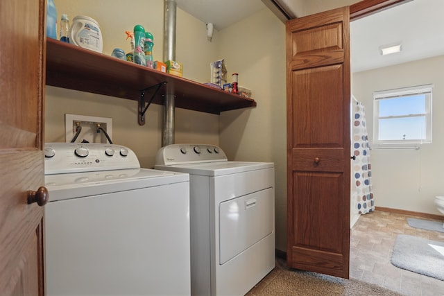 washroom with stone finish floor, baseboards, washer and dryer, and laundry area