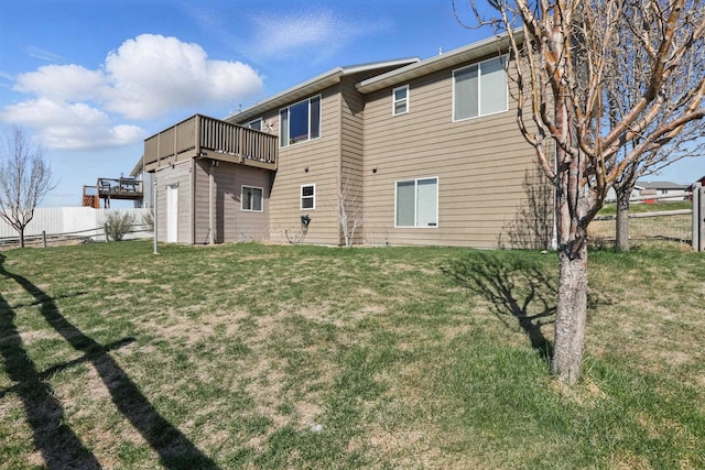 rear view of house featuring fence and a lawn