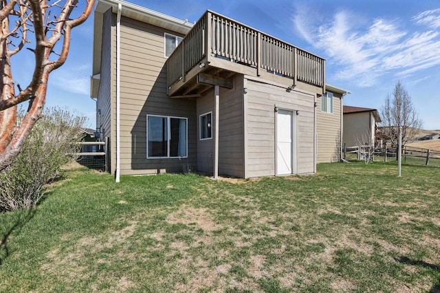 rear view of property featuring a lawn, fence, and a deck