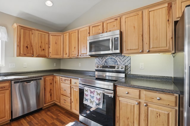 kitchen with recessed lighting, lofted ceiling, stainless steel appliances, dark countertops, and dark wood-style flooring