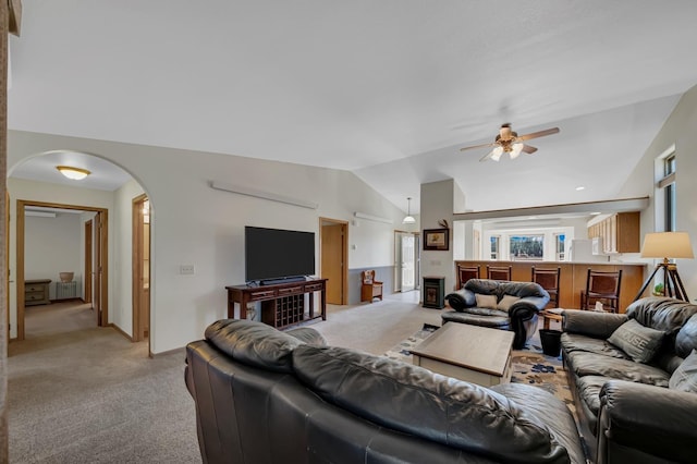 living room featuring ceiling fan, arched walkways, light colored carpet, radiator, and lofted ceiling