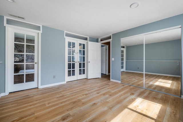 unfurnished bedroom with baseboards, french doors, wood finished floors, and visible vents