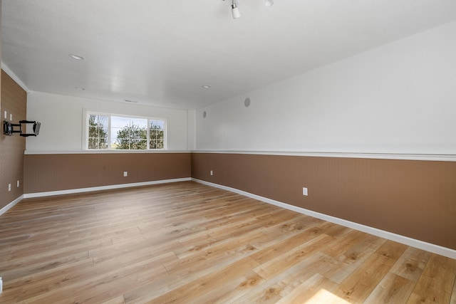 empty room with wood walls, baseboards, a wainscoted wall, and wood finished floors