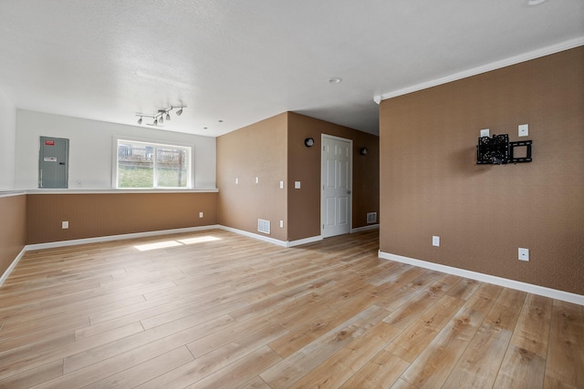 empty room with light wood-style floors, electric panel, and baseboards