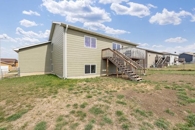 rear view of house with a lawn, a wooden deck, stairway, and fence