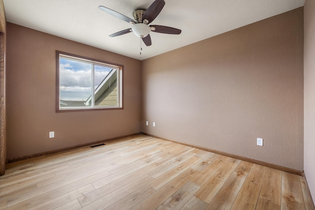spare room featuring baseboards, light wood-style flooring, visible vents, and ceiling fan