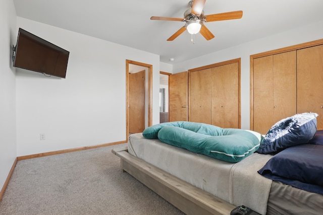 bedroom with carpet floors, baseboards, ceiling fan, and two closets