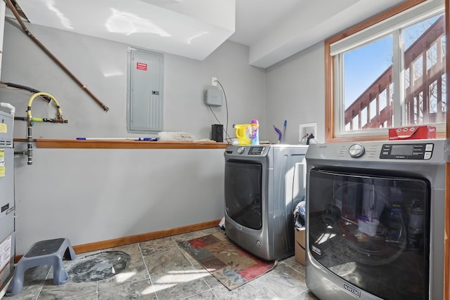 clothes washing area featuring electric panel, washer and clothes dryer, baseboards, stone finish floor, and laundry area