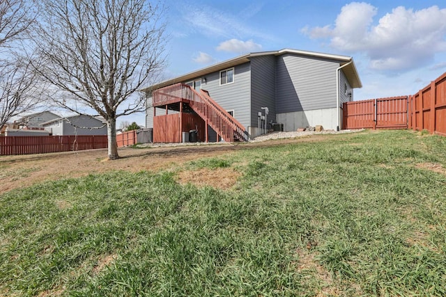 rear view of property with a wooden deck, a yard, a fenced backyard, and stairway