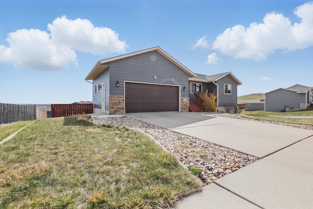 ranch-style home featuring a front lawn, fence, driveway, and a garage