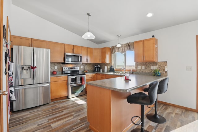 kitchen with a peninsula, tasteful backsplash, light wood finished floors, and stainless steel appliances