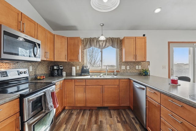 kitchen featuring stainless steel appliances, a sink, dark wood finished floors, decorative backsplash, and brown cabinetry