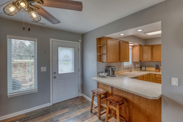 kitchen with light countertops, a sink, dark wood finished floors, and a healthy amount of sunlight