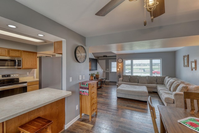 living room featuring dark wood-type flooring, baseboards, ceiling fan, and recessed lighting