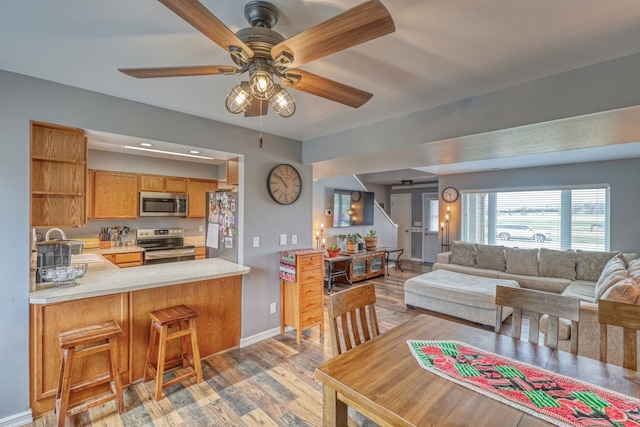 living area with light wood-type flooring, baseboards, and ceiling fan