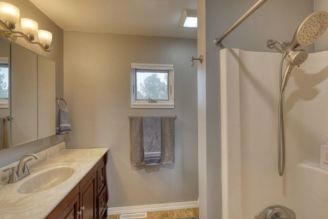 full bathroom with visible vents, baseboards, walk in shower, and vanity