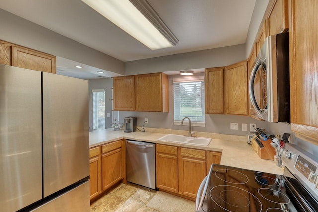 kitchen with stainless steel appliances, light countertops, a sink, and recessed lighting