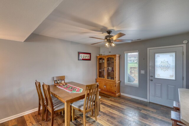 dining space featuring a ceiling fan, baseboards, and dark wood-type flooring
