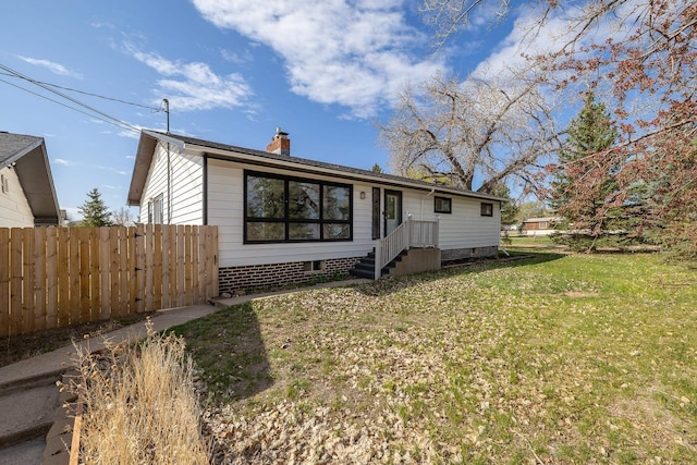 exterior space with fence, a chimney, and a yard