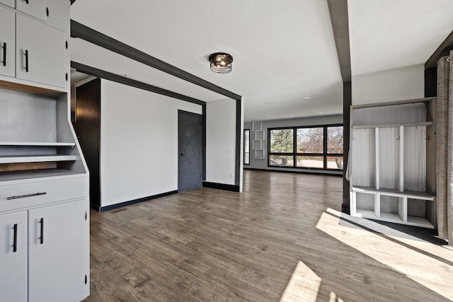 unfurnished living room with baseboards and dark wood-style flooring
