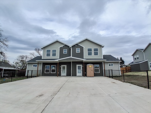 view of property featuring concrete driveway, fence, and board and batten siding