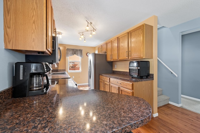 kitchen featuring dark countertops, a textured ceiling, baseboards, a peninsula, and freestanding refrigerator