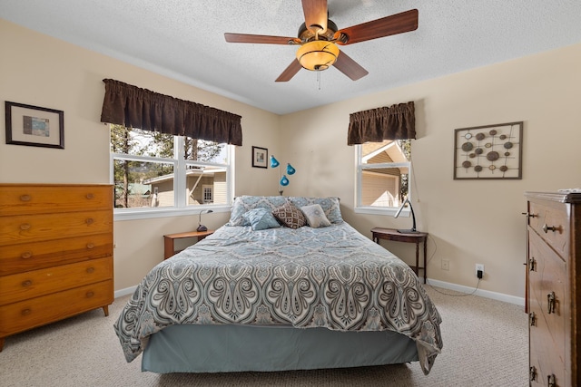 carpeted bedroom with a textured ceiling, a ceiling fan, and baseboards