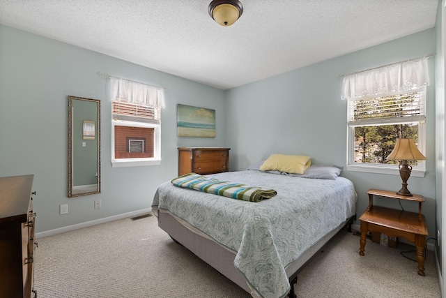 carpeted bedroom with baseboards, a textured ceiling, and visible vents