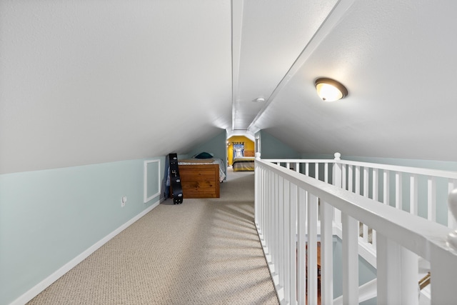 interior space with vaulted ceiling, carpet flooring, and baseboards