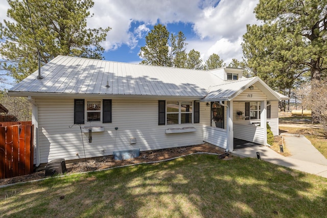 ranch-style house with fence, a front lawn, and metal roof