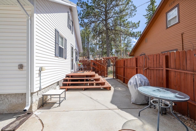 view of patio with a wooden deck, area for grilling, and fence