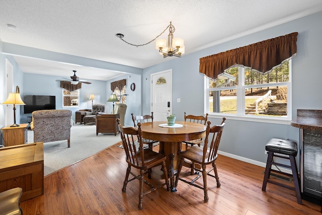 dining room featuring baseboards, wood finished floors, and ceiling fan with notable chandelier
